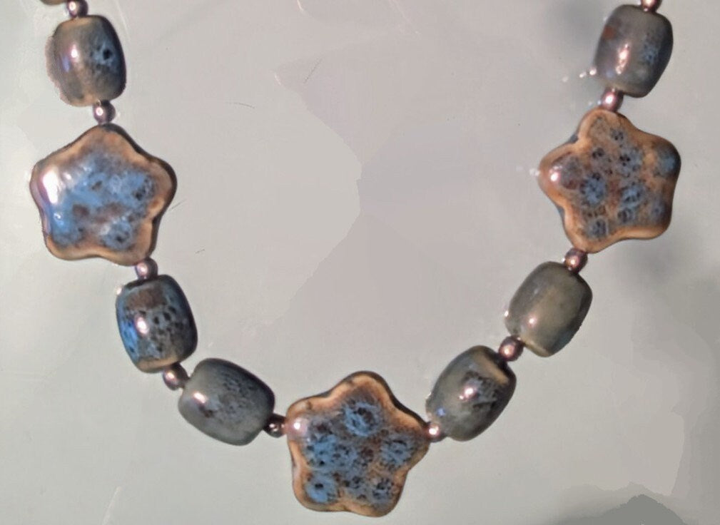 Artisan Ceramic Chunky Necklace. With shades of blue and tan, oval-shaped beads interspersed with star-shaped focals. Glossy with texture.