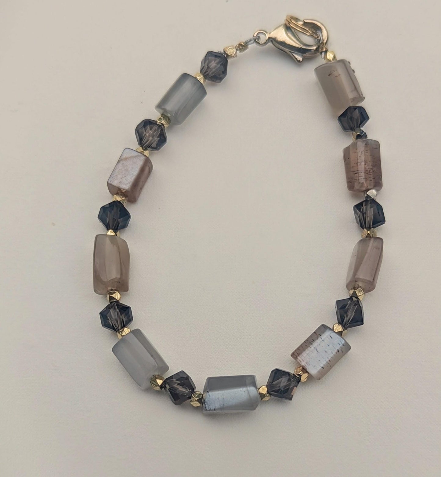 The bracelet, made of horizontal Moon Stone beads contrasted with faceted Smoky Topaz beads, and interspersed with bicone gold spacers.
